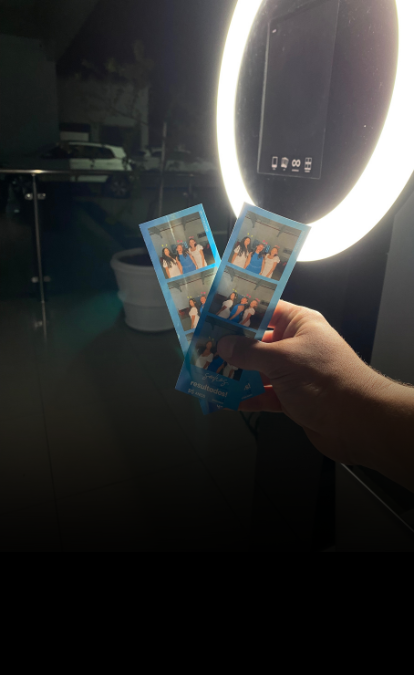 A hand holding freshly printed photo strips from a photo booth